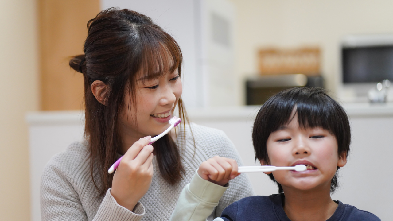 Mother and child brushing their teeth together at home, practicing healthy dental care habits.