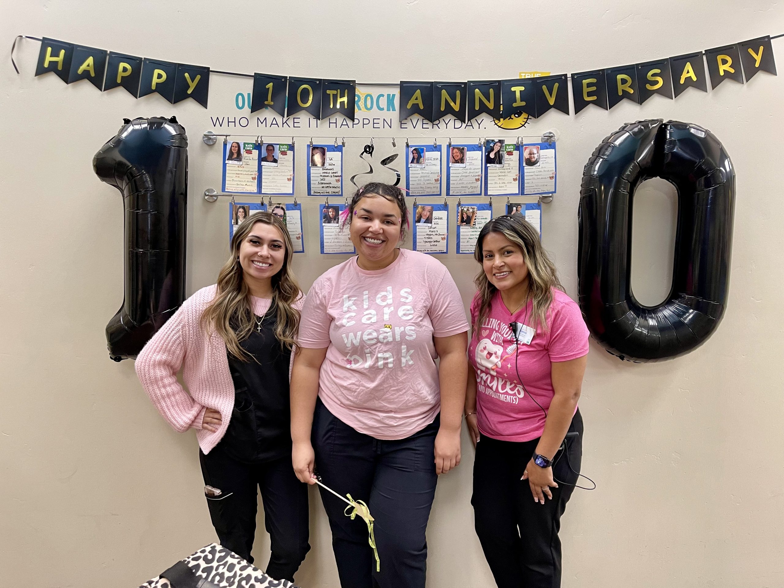 Team members at Kids Care Dental Tracy standing and smiling in front of 10 year party decorations