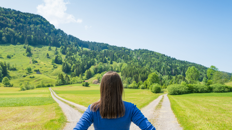 A person stands at a fork in the road, symbolizing the decision of when to hire a marketing agency versus continuing DIY marketing.