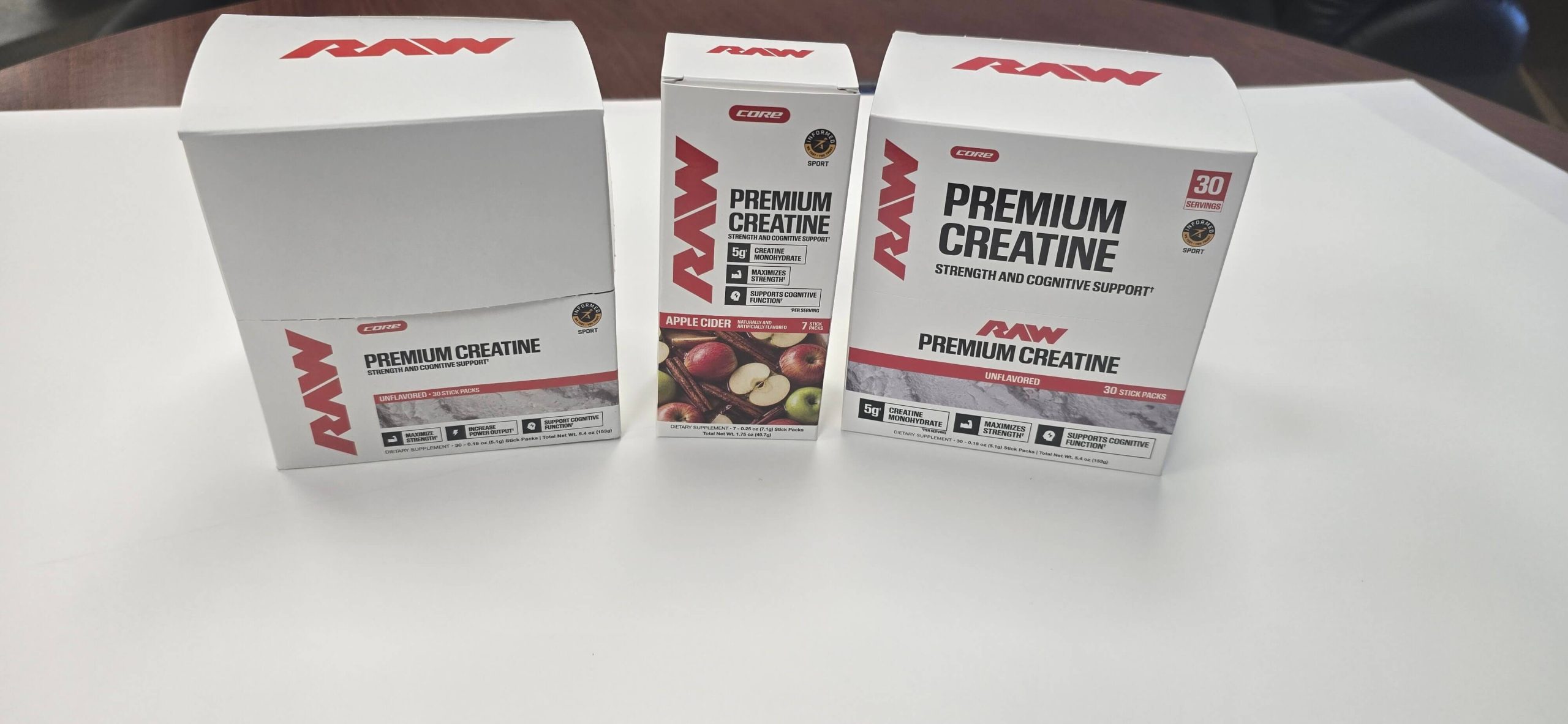 Three RAW Nutrition Premium Creatine folding cartons, including 30-count stick pack display boxes and a 7-count apple cider carton
