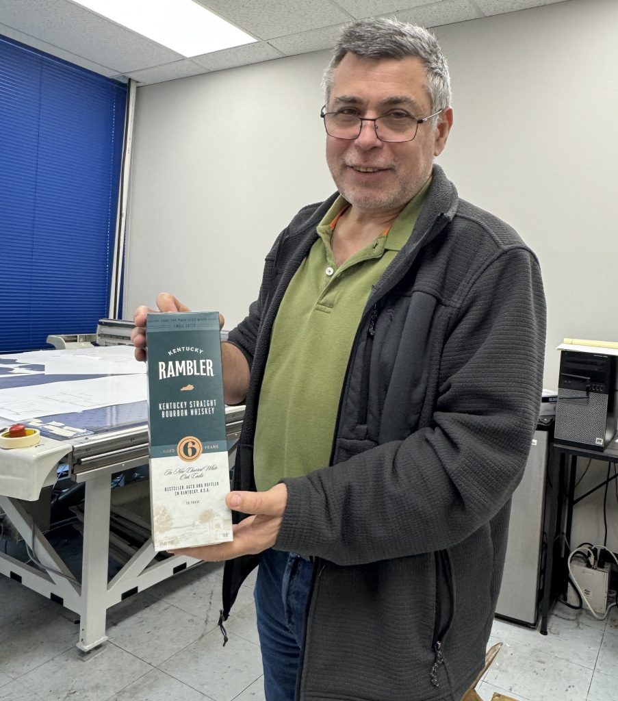 Yan Sherman, Head of Design at Pak-Pro, holding a Kentucky Rambler whiskey carton from the award-winning project.